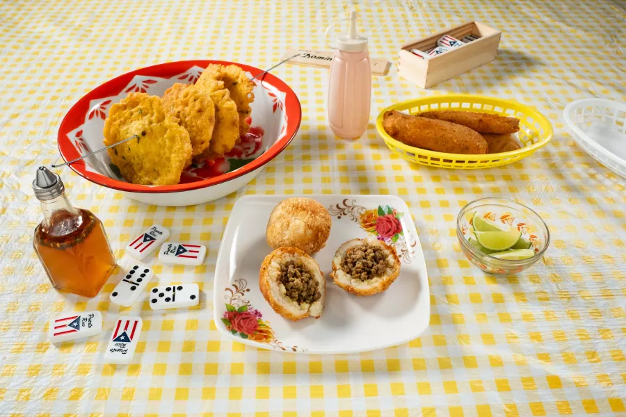 Puerto Rican fritters served on colorful plates with sauces and lime.